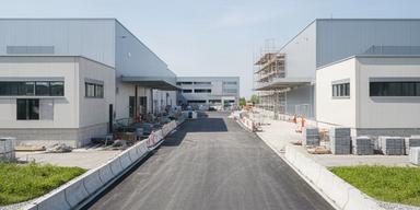 Neuer Gewerbepark in Belp mit breiter Zufahrt und sichtbaren Fassadenarbeiten